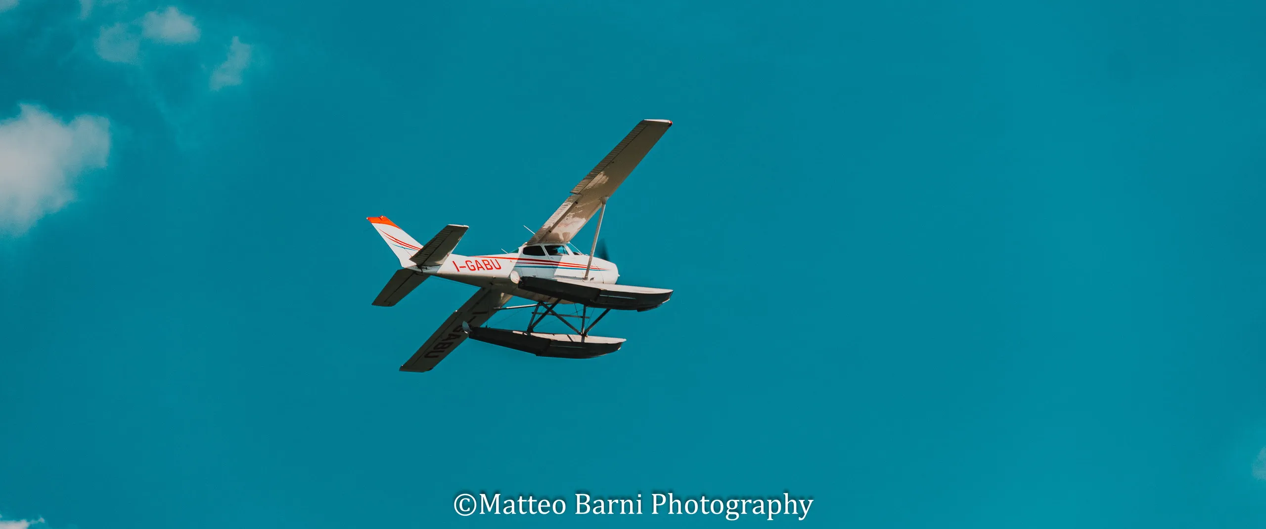 Un idrovolante bianco e rosso in volo nel cielo azzurro